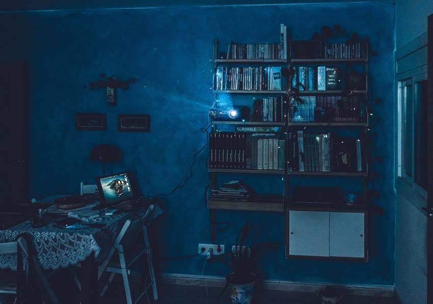 Foto de una estancia de tono azul con librería y un proyector